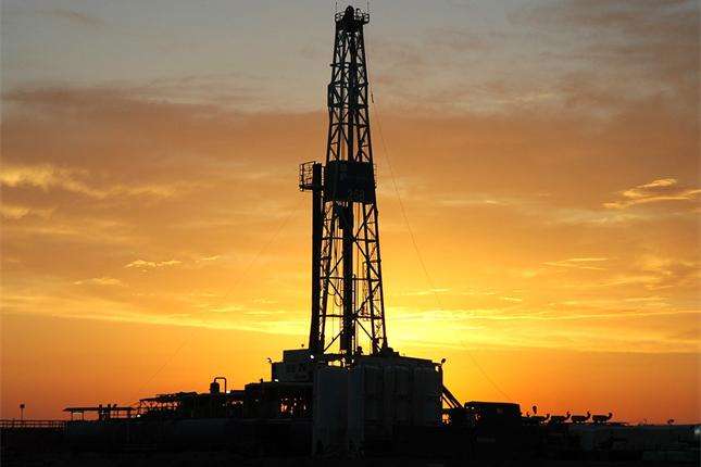 Drilling rig silhouetted against an orange sunset